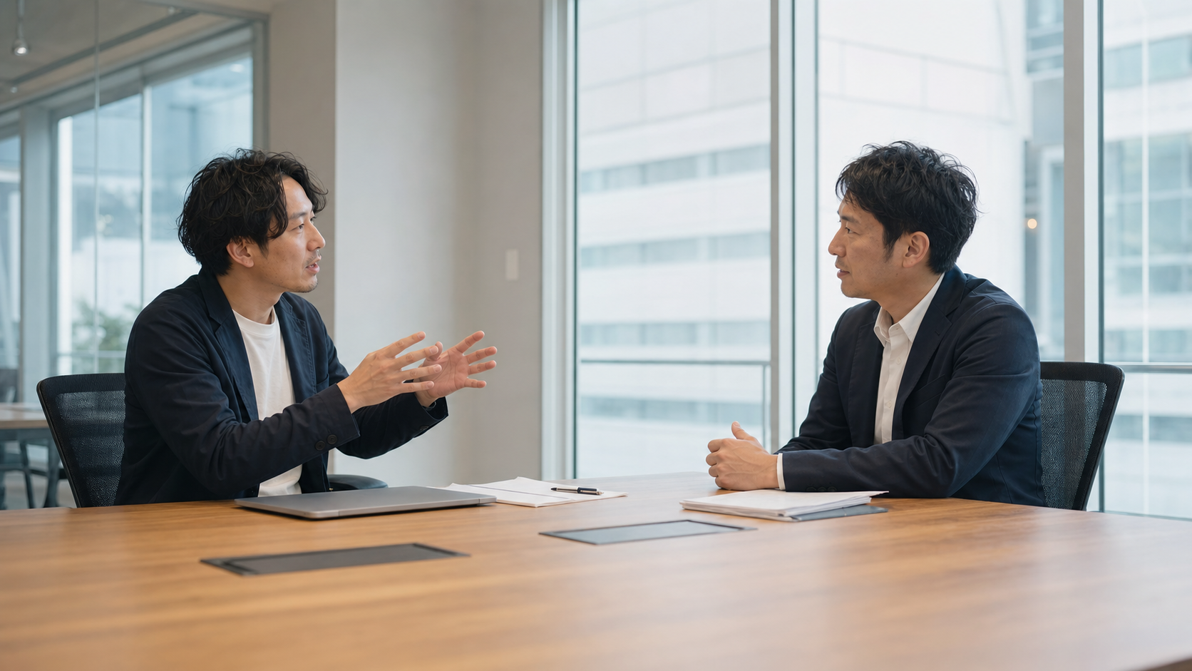 オフィスの会議室でディレクターが企業担当者と採用動画の内容について打ち合わせをしている場面、自然光、落ち着いた雰囲気