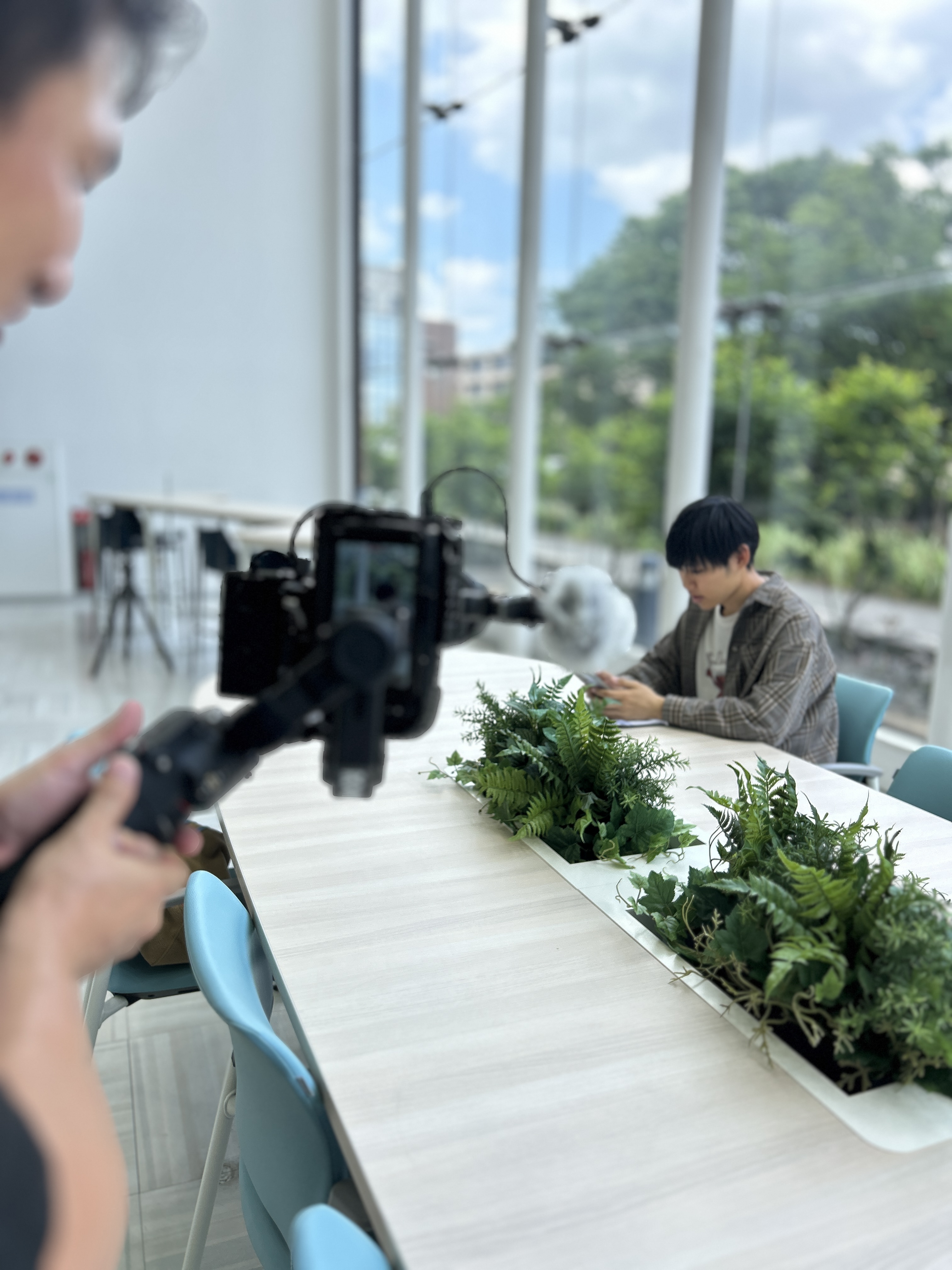 採用動画・求人動画の撮影現場で、明るい室内で出演者をカメラで撮影している様子
