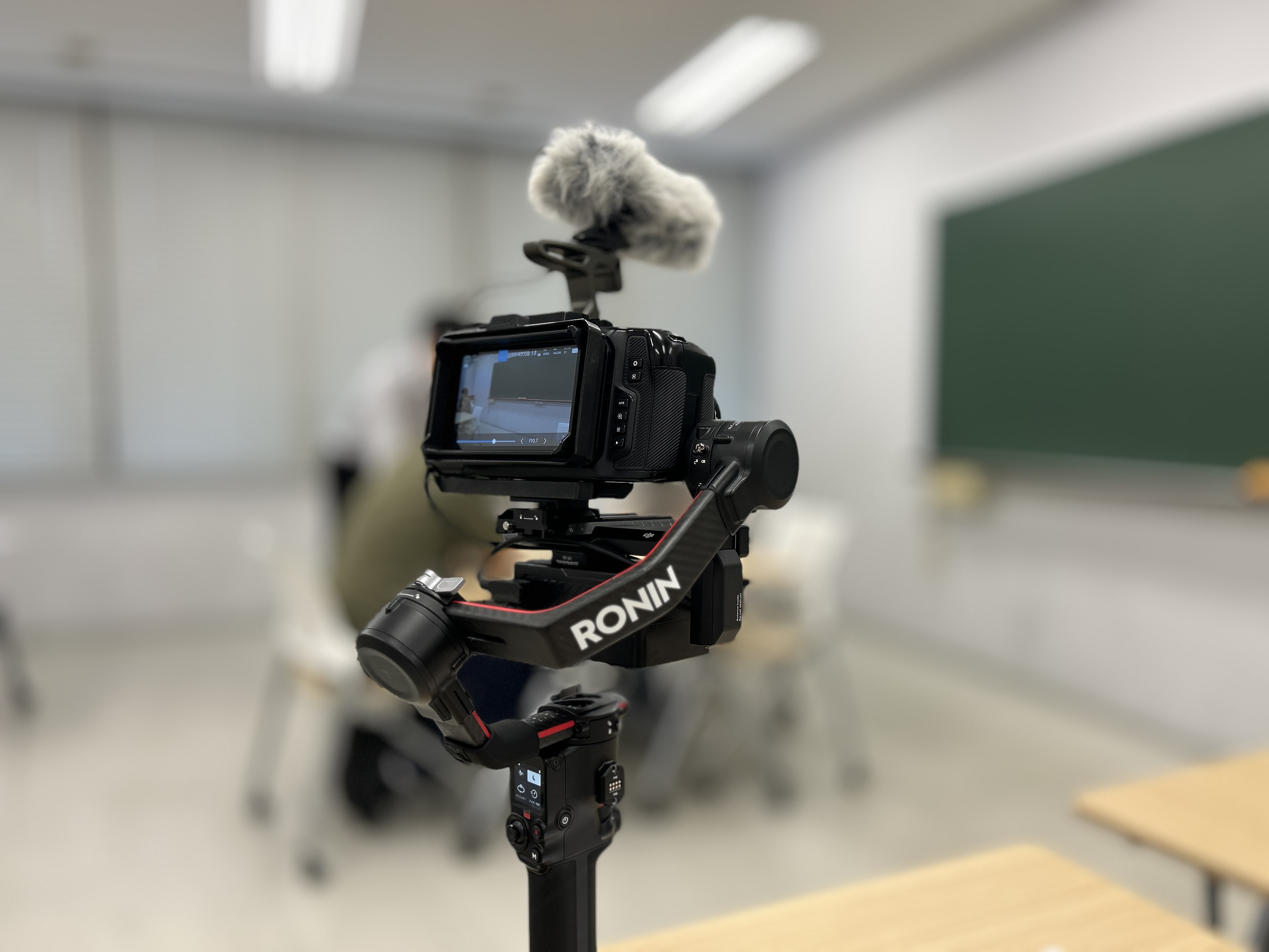 教室内でジンバルスタビライザーにカメラとショットガンマイクを搭載した撮影機材のクローズアップ